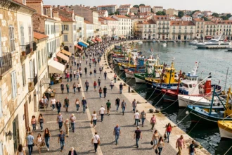 Vue panoramique du Vieux-Port de Marseille avec des habitants traversant le quai, illustrant la densité de population de la ville